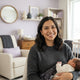A happy, diverse parent smiling in a modern nursery with soft lavender and cream decor.